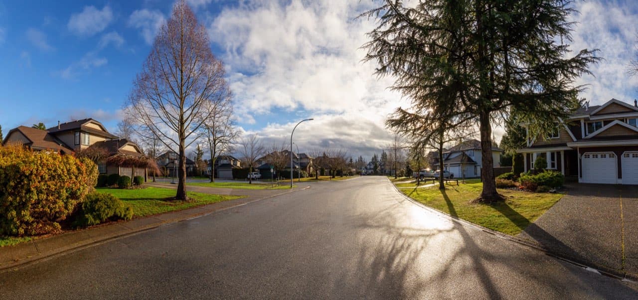 Suburban street with smooth asphalt road and concrete sidewalks