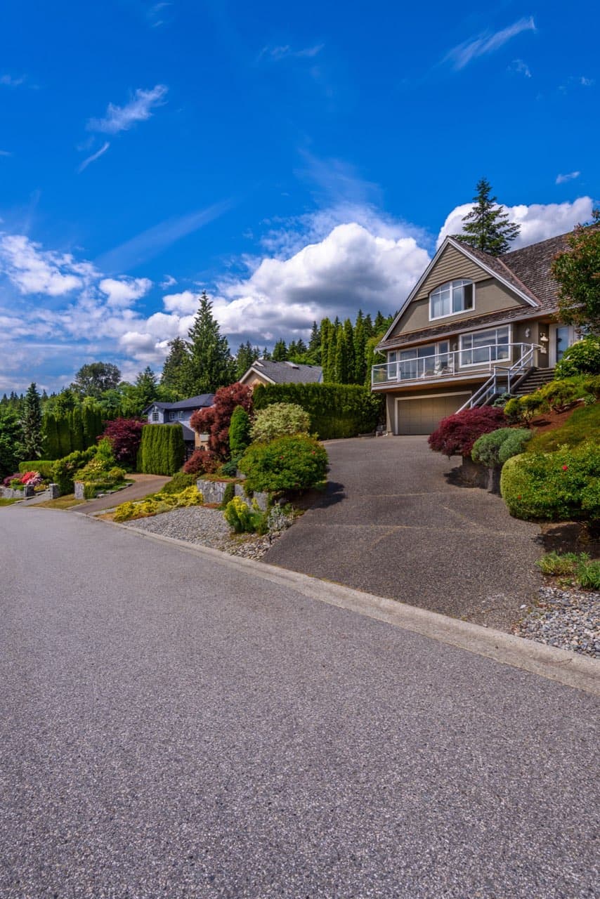 Newly paved black asphalt driveway in front of a suburban home