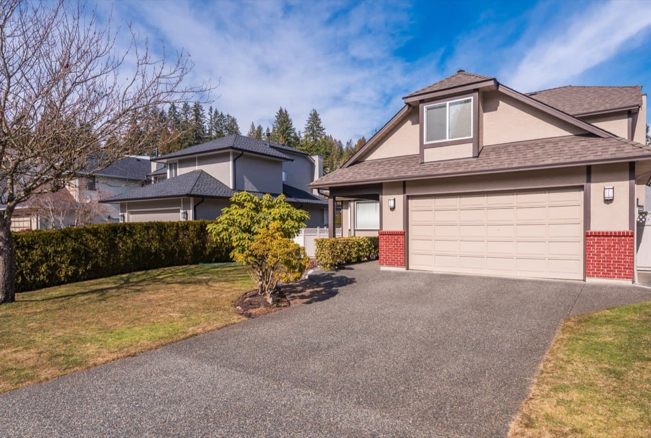 Two-story luxury home with a wide, freshly paved driveway