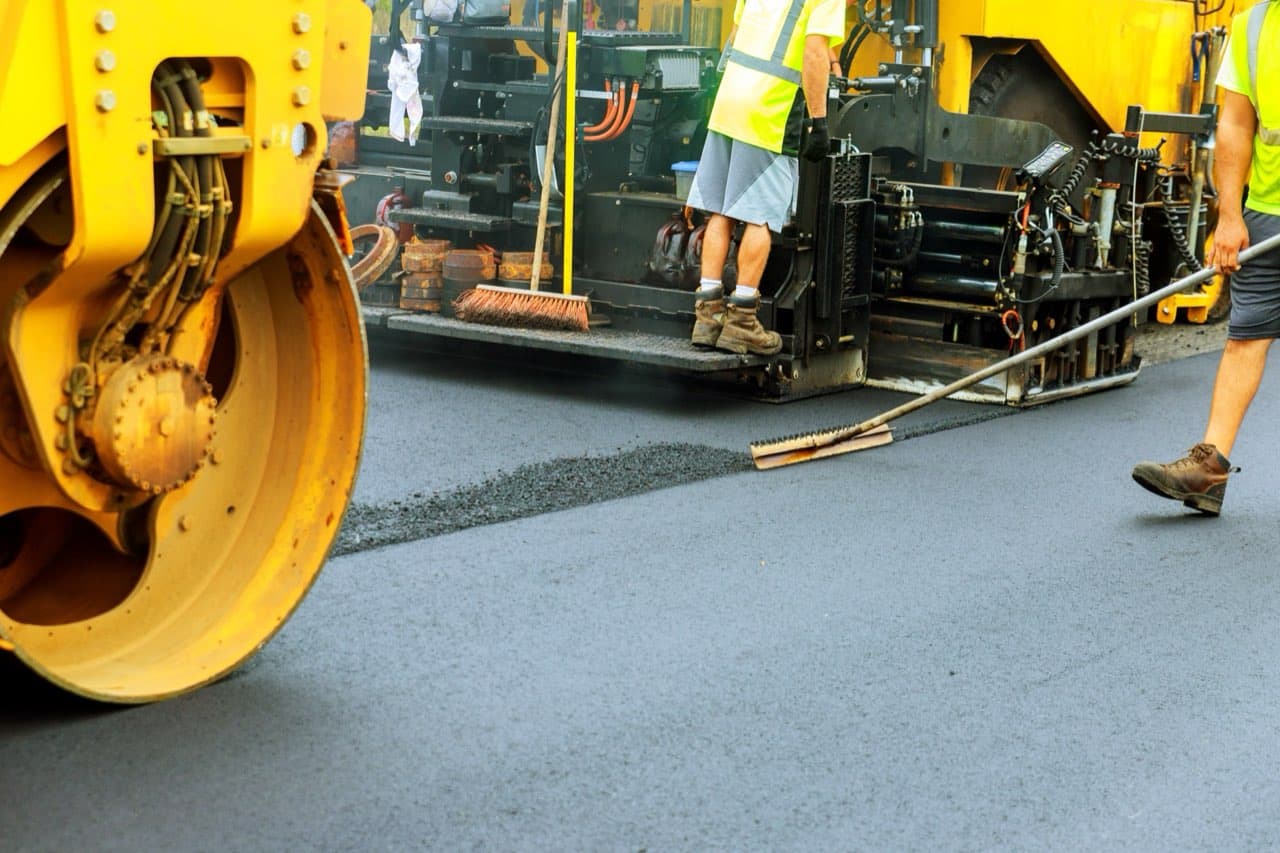Paving crew and steam roller working on a road construction site