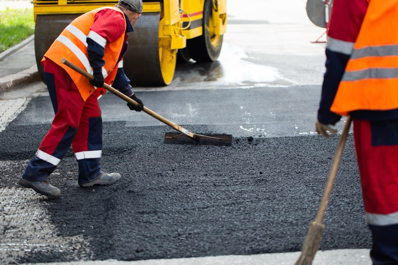 Workers patching a damaged asphalt road surface